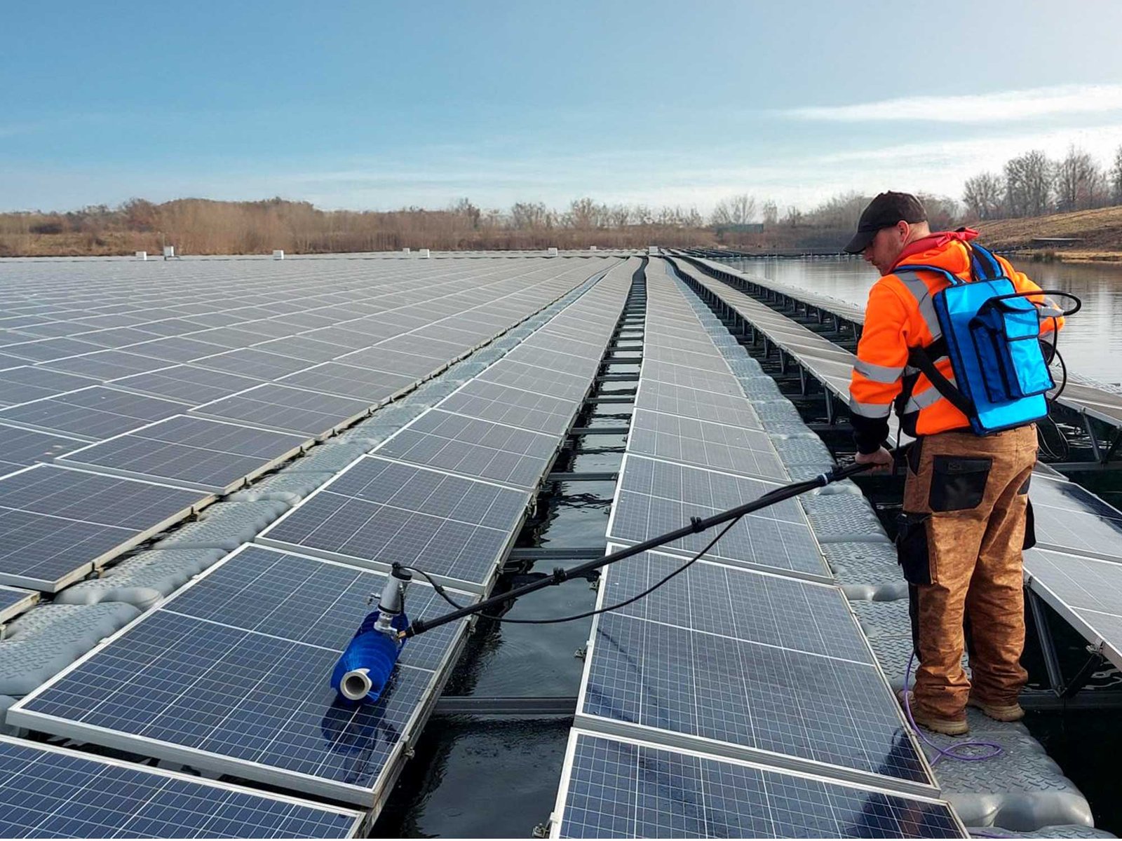 Técnico realizando la limpieza y mantenimiento de paneles solares sobre un tejado con un cepillo telescópico de microfibra